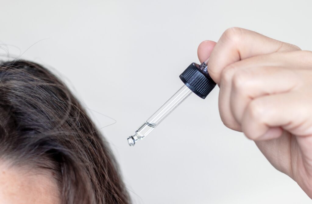 Woman applying serum oil on wet hair with pipette