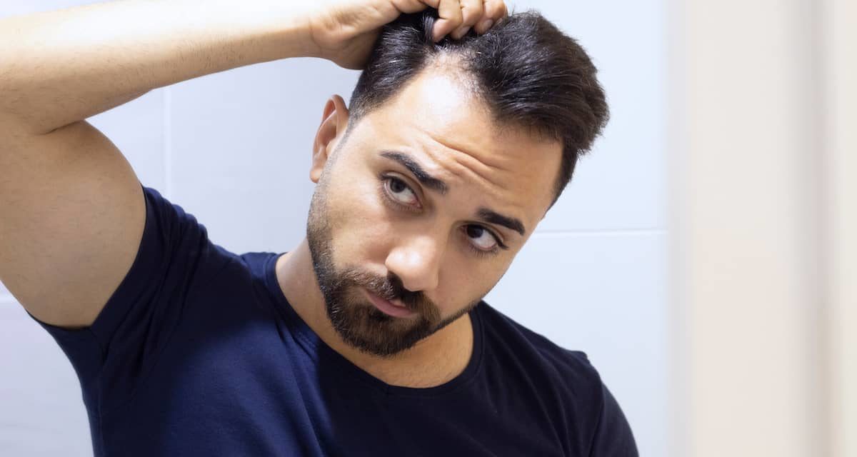 Man wondering why do hair transplants fail? while looking at thin hair in the mirror