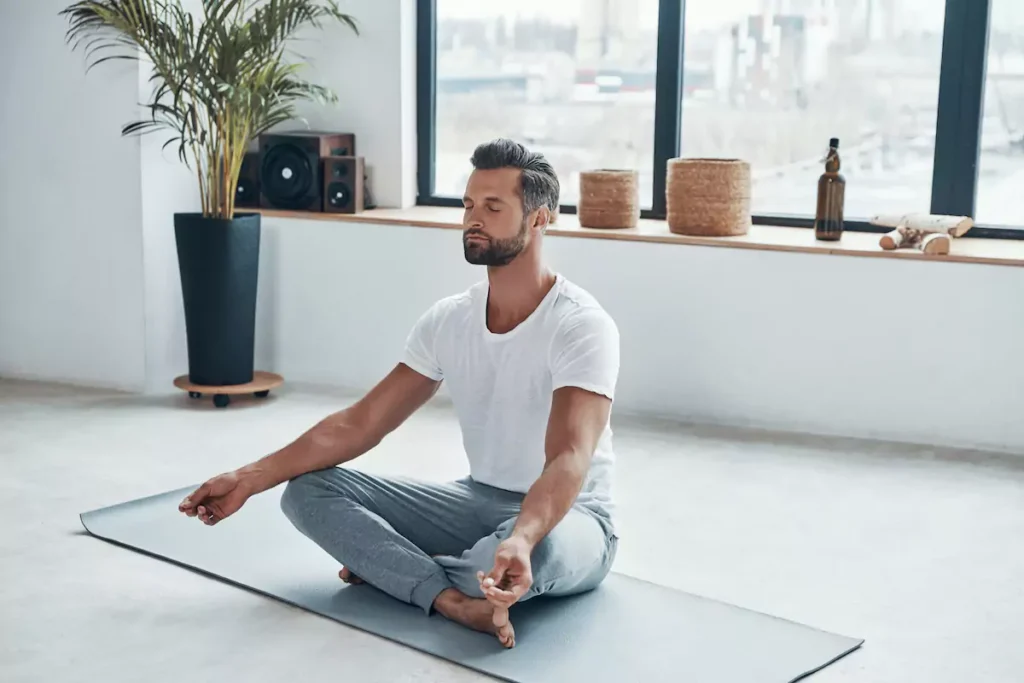 Un homme est assis dans une posture de yoga détendue.
