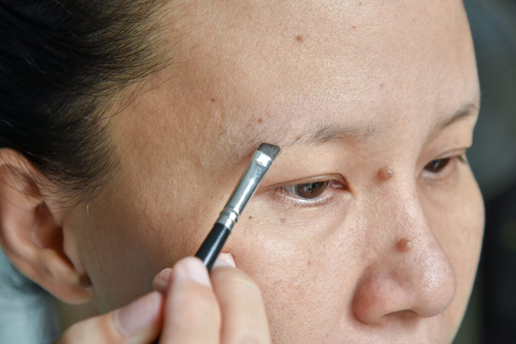 Asian woman applying makeup on her sparse eyebrows