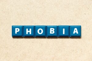 Płytki liter alfabetu ułożone w słowo "phobia" na drewnianym tle