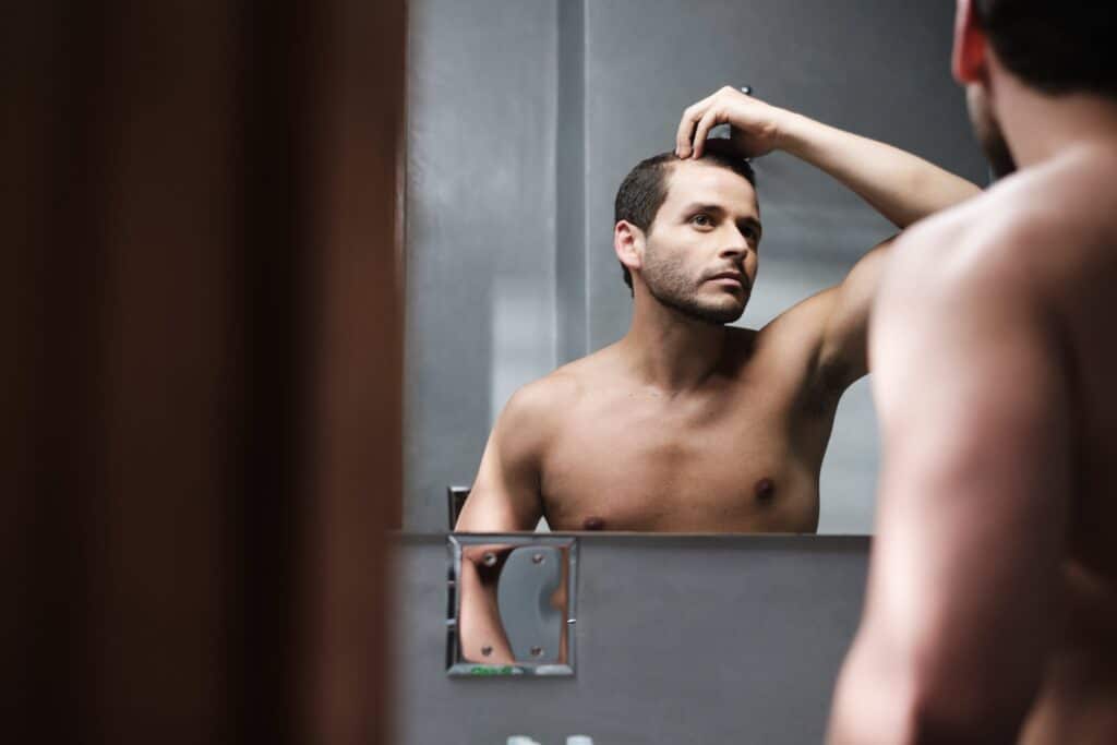 Man using finasteride after a hair transplant looking at the mirror