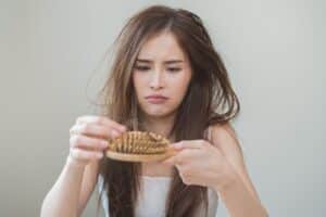 Woman looking at her broken hair wondering how to fix them