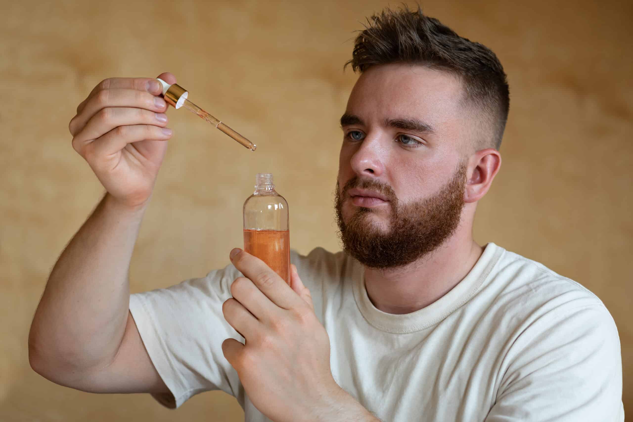 Hombre sosteniendo un frasco de cristal con un medicamento que contiene Minoxidil