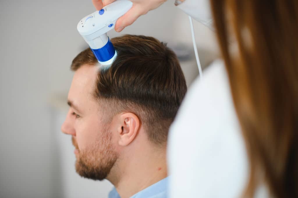 Un médico examina el cabello de un hombre