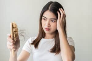 Una mujer que sufre alopecia femenina se mira el pelo perdido después de peinarse