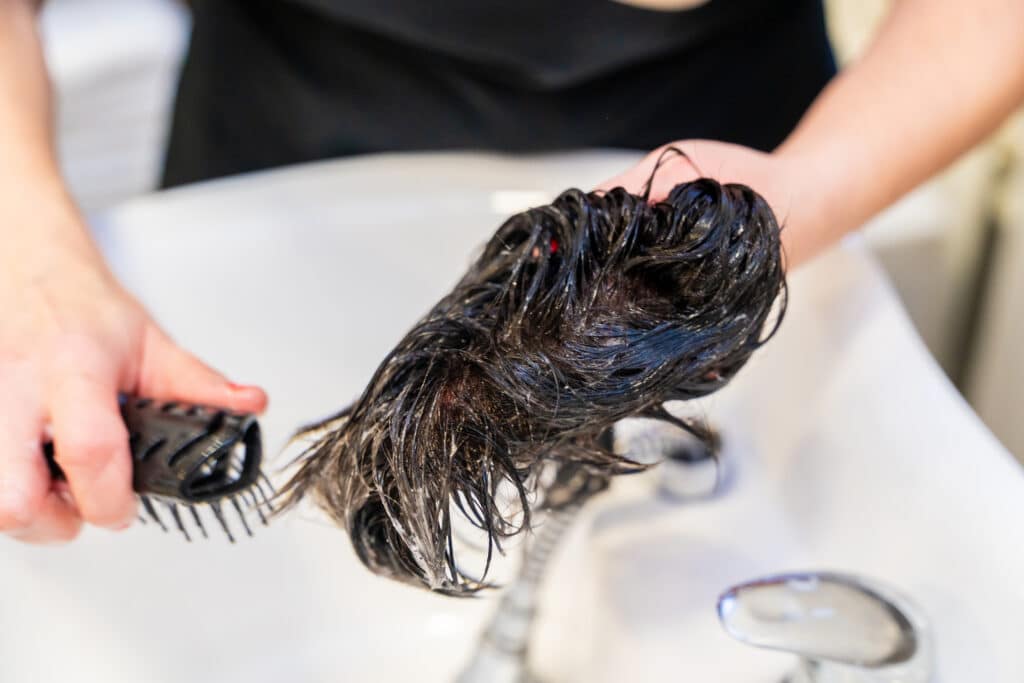 Estilista peinando una prótesis capilar en la peluquería
