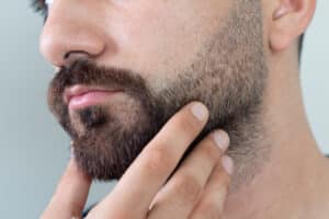 Uomo con barba poco folta riflette su come infoltire la barba