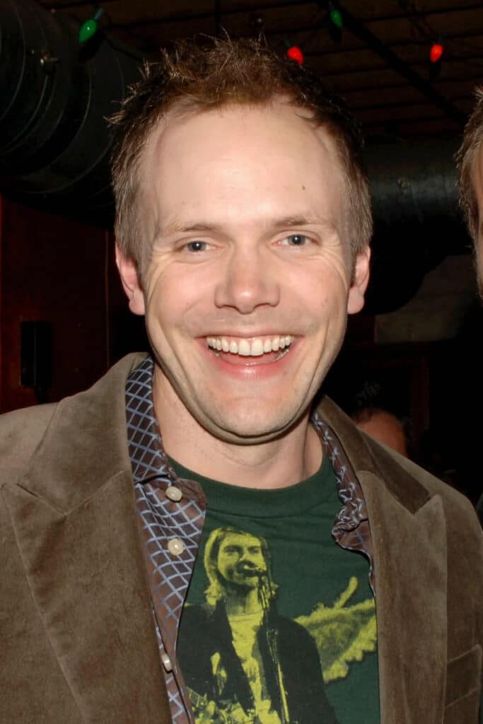 Joel McHale smiling at an event in his younger years, displaying signs of early hair loss