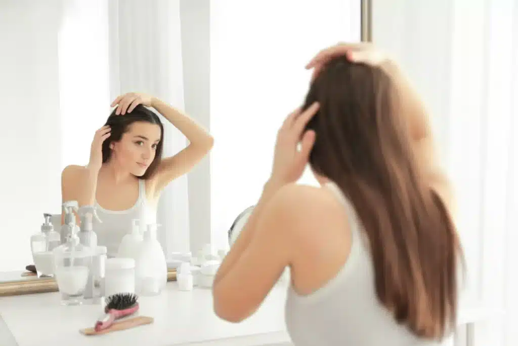Donna guarda i propri capelli allo specchio