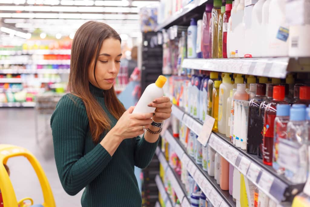 Mujer comprobando lo que pone en un bote de champú en una tienda