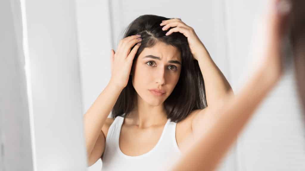 Ragazza guarda i capelli allo specchio