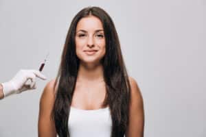 Cosmetologo con in mano una siringa per la mesoterapia capelli vicino a una paziente donna