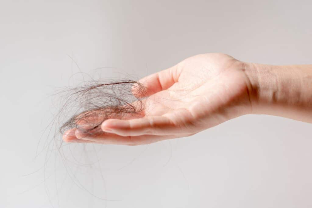 Main tenant une mèche de cheveux perdus – signe visible de perte de cheveux pouvant indiquer quand faire une greffe de cheveux