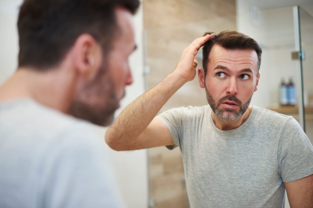Homme devant le miroir s'inquiétant d'une perte de cheveiu liée à la créatine