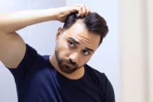 Homme observant ses cheveux après traitement au dutastéride cheveux