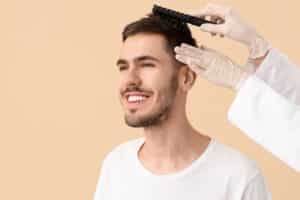 Medico per trapianto di capelli che spazzola i capelli di un ragazze