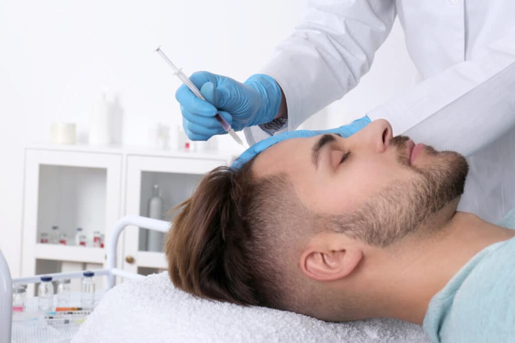Uomo con problemi di perdita di capelli che riceve un'iniezione per un trapianto di capelli