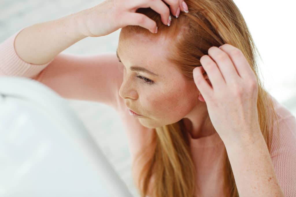 Donna controlla i suoi capelli allo specchio