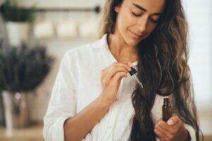 Donna usa uno dei rimedi naturali per la caduta dei capelli, delle gocce di olio vegetale.