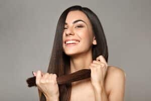 Una mujer se sujeta su fuerte cabello tras descubrir cómo fortalecer el cabello