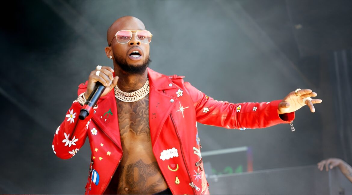 Tory Lanez wearing a red jacket & a mic in his hand