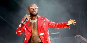 Tory Lanez w czerwonej kurtce, z mikrofonem w dłoni