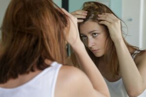 Donna controlla i propri capelli allo specchio chiedendosi come capire se sta perdendo i capelli