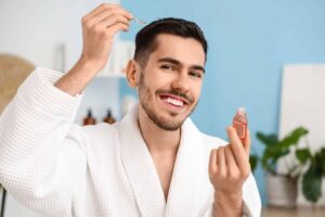 Hombre que se aplica un sérum para el crecimiento del cabello 6 meses después del trasplante