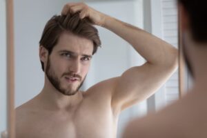 Uomo si guarda allo specchio frustrato dal ciuffo ribelle