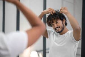 Uomo con capelli ricci, uno dei tipi di capelli, si guarda allo specchio
