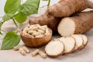 Yamswurzel mit geschnittenen Wurzelstücken und Kapseln als Symbol für Wild Yam als Nahrungsergänzung bei Haarausfall.